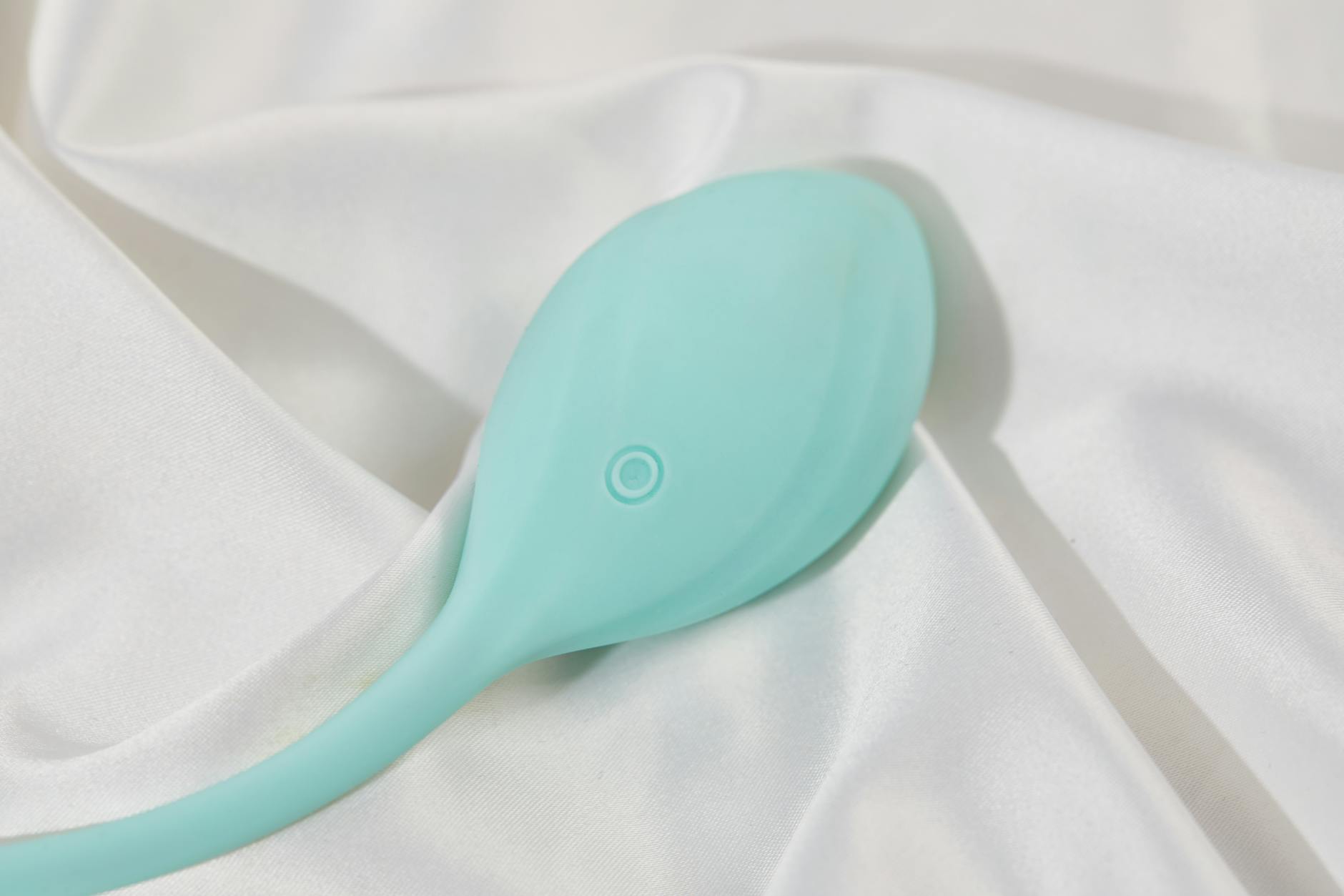 Teal lemon vibrator resting on white silk fabric, symbolizing self-care and personal pleasure