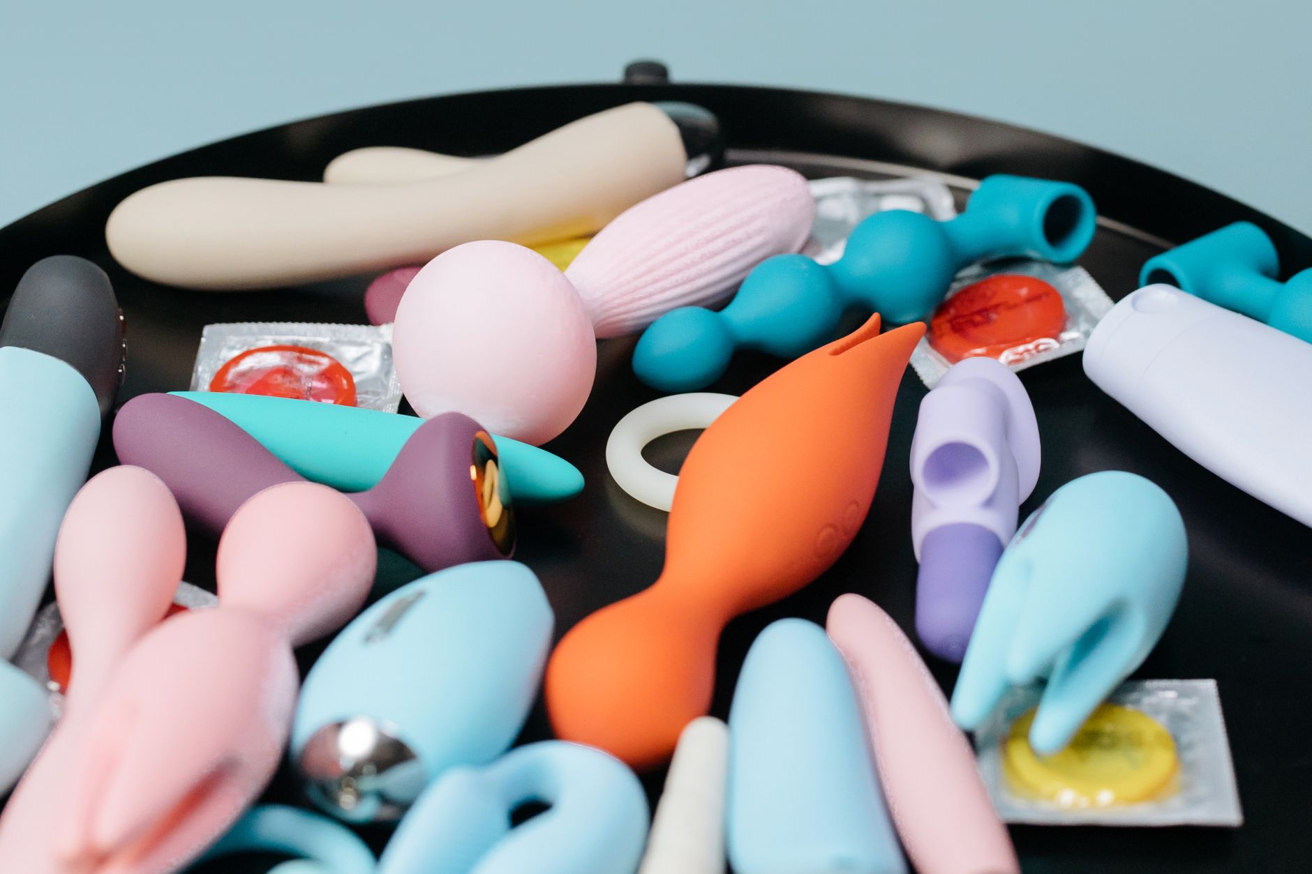 Collection of colorful clitoral vibrators arranged on a bright yellow surface, showcasing various designs and styles