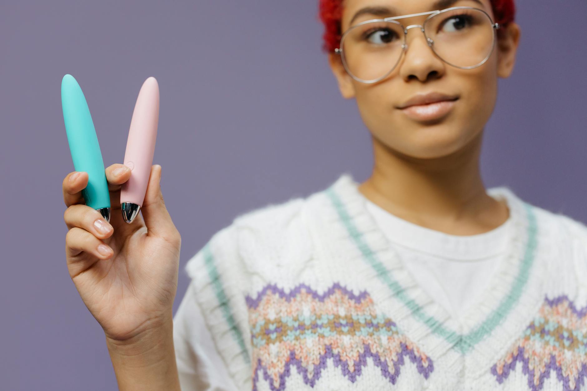 Una donna tiene in mano un vibratore colorato su sfondo viola, simboleggiando l'auto-amore e la sessualità consapevole