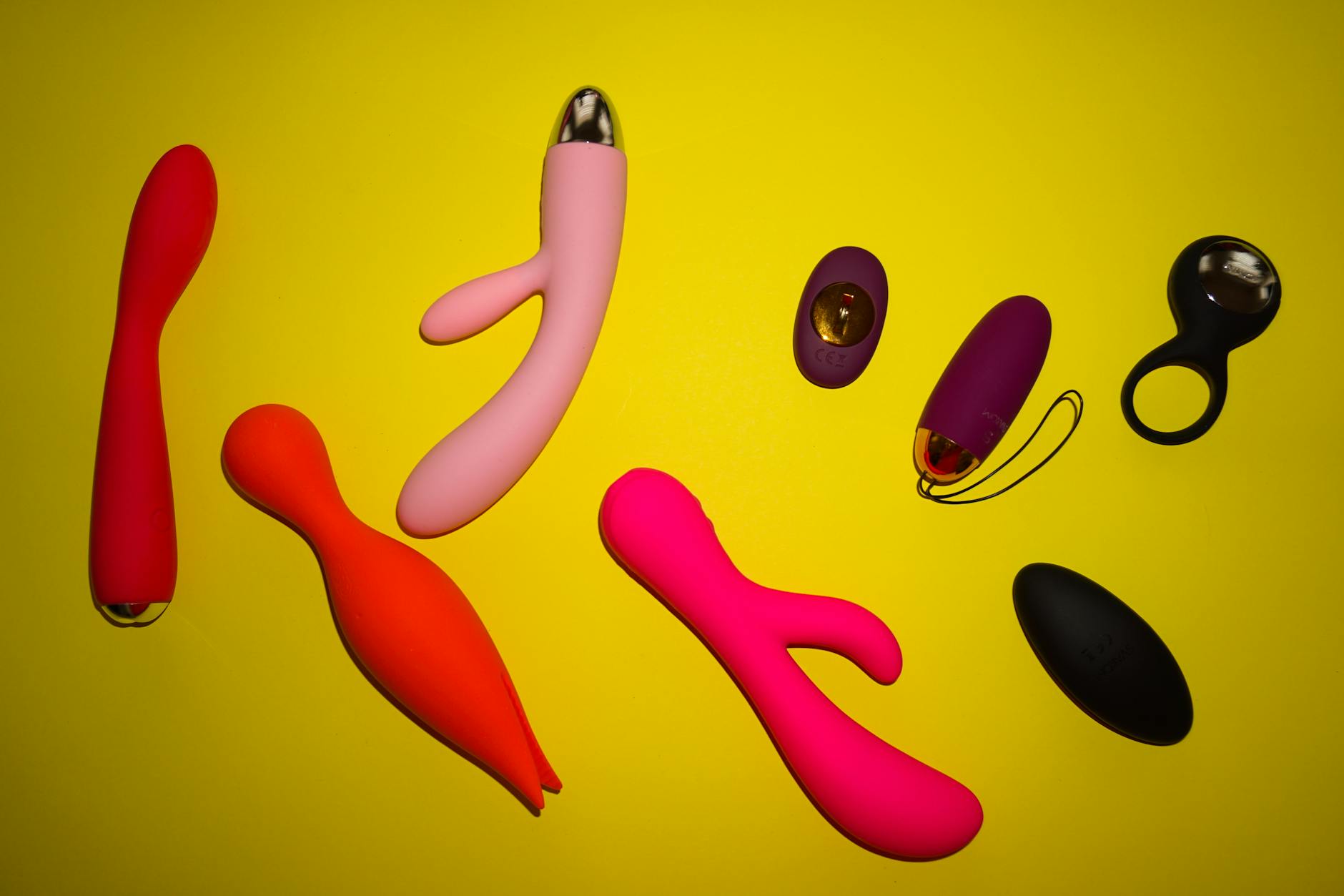 Vibratori colorati disposti su sfondo giallo brillante, mostrando diversità e design moderno