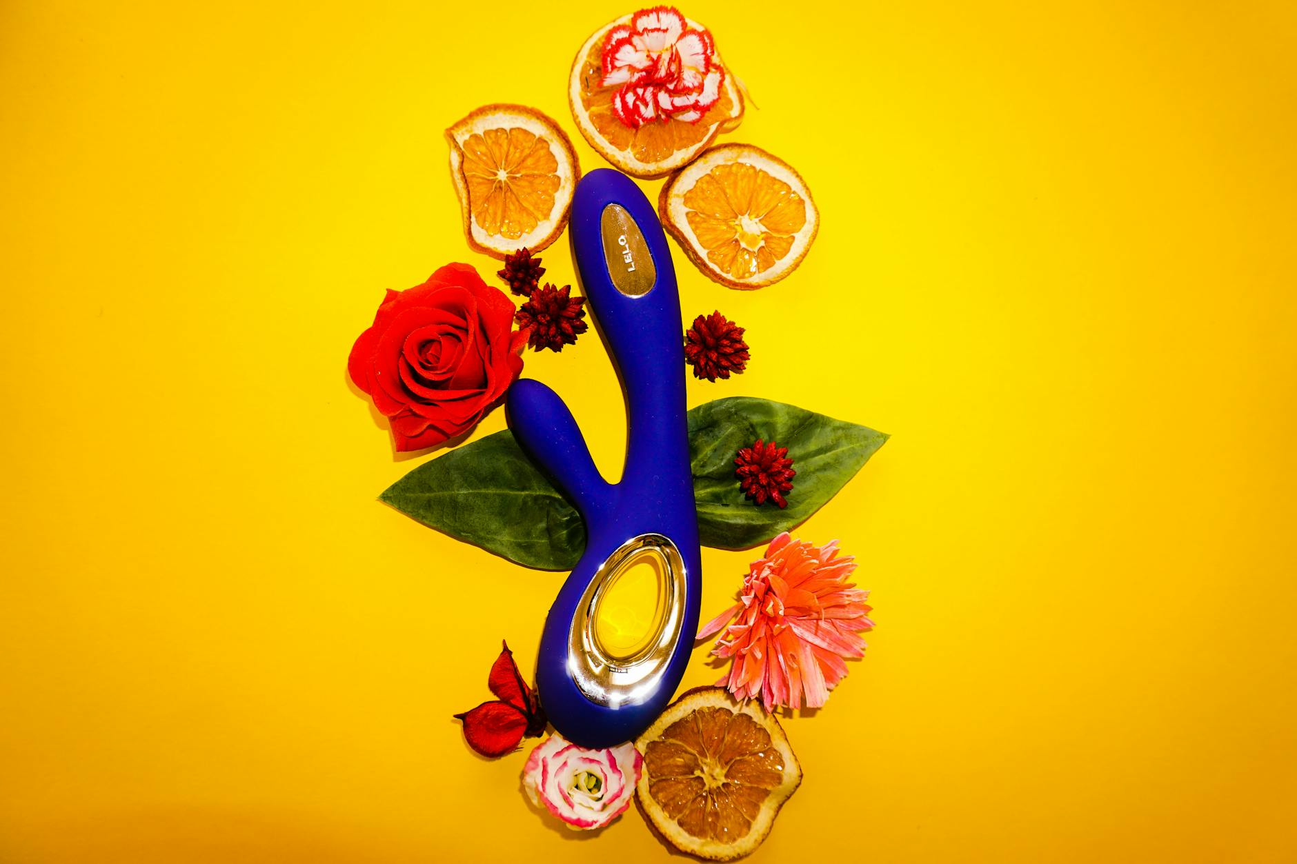 Colorful lemon vibrator surrounded by flowers and citrus slices on a yellow background